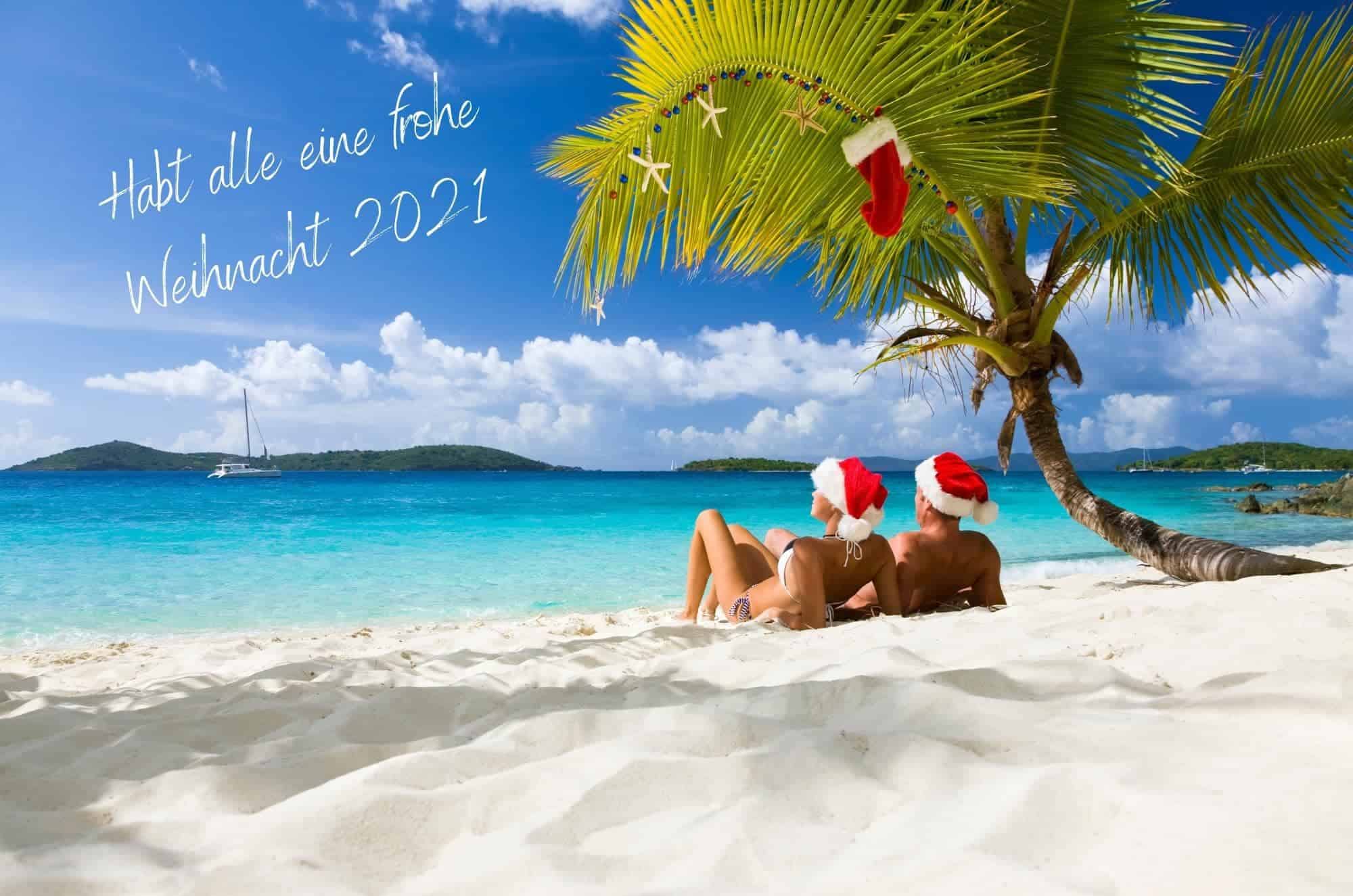 Merry Xmas 2021 zeigt ein Pärchen mit Weihnachtsmann-Mütze an einem Karibikstrand!